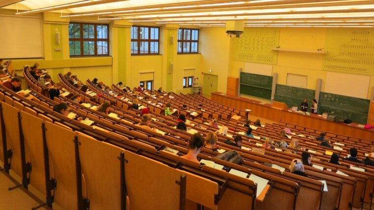 Studierende sitzen während einer schriftlichen Klausur in einem großen Hörsaal