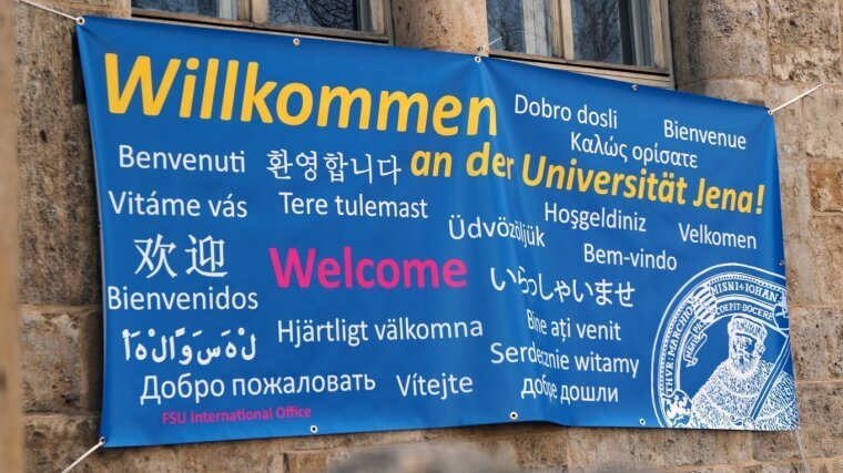 Ein Banner mit der Aufschrift "Willkommen an der Universität Jena" in mehreren Sprachen